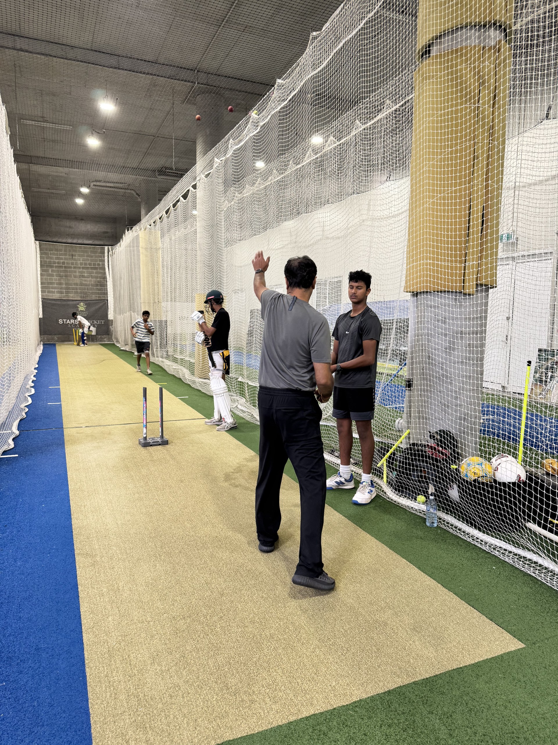 Coach bowling to batter in indoor lane